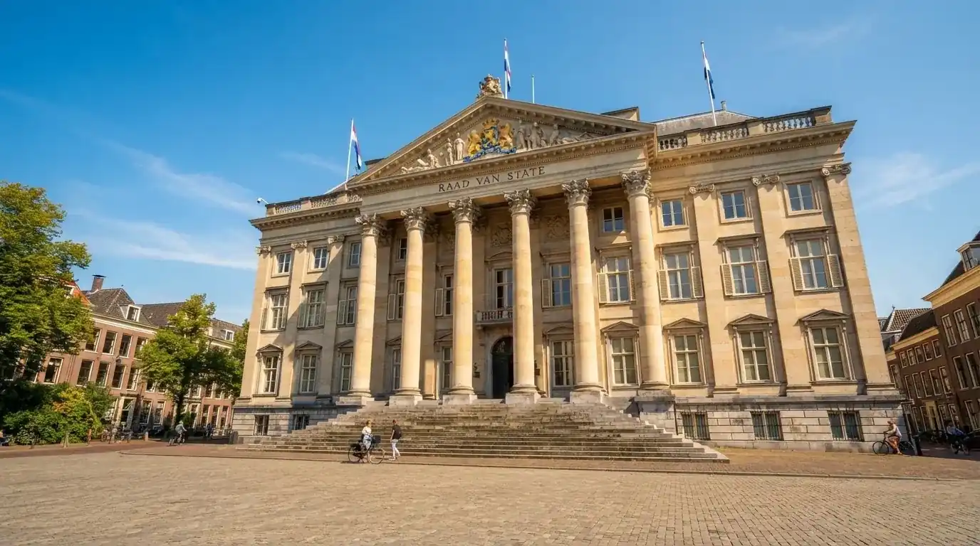 Een statig gerechtsgebouw met brede trappen en zuilen staat onder een heldere hemel in een Nederlandse stad.